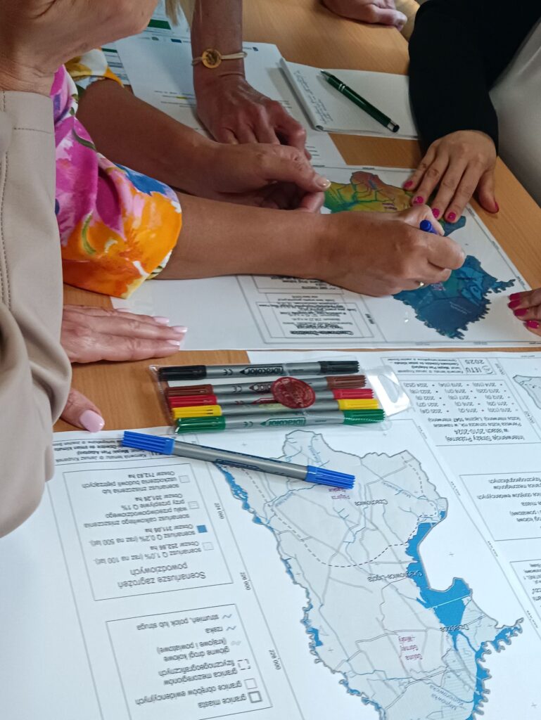 Praca grupowa nad mapą z wykorzystaniem markerów podczas warsztatów dotyczących adaptacji do zmian klimatu.