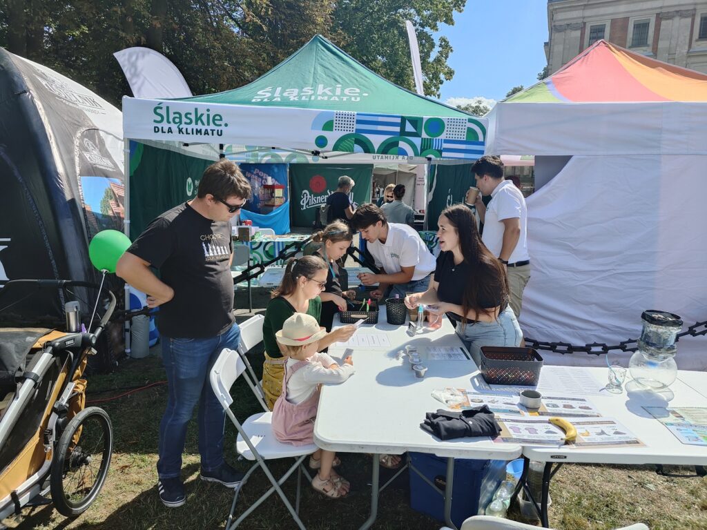 Uczestnicy wydarzenia biorą udział w quizach i aktywnościach edukacyjnych na stoisku Mobilnego Punktu Edukacji i Inspiracji Klimatycznej
